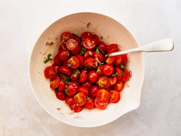Tossing the tomato salad ingredients with the balsamic dressing.