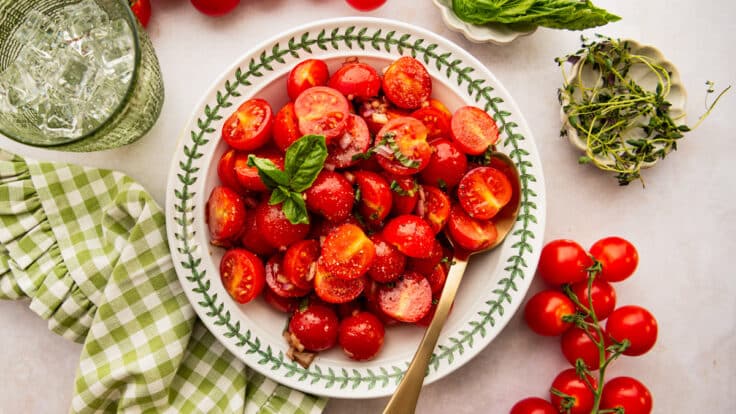 Horizontal overhead image of tomato basil salad in a green and white bowl.