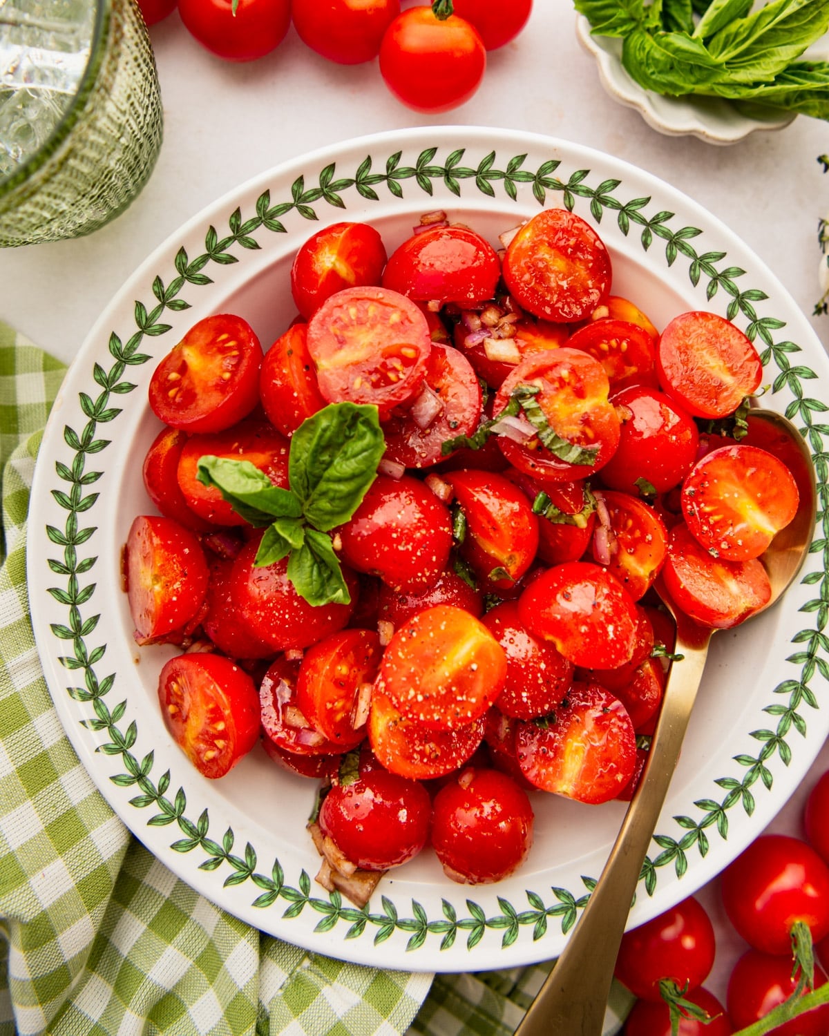 Overhead image of tomato basil salad in a green and white bowl.