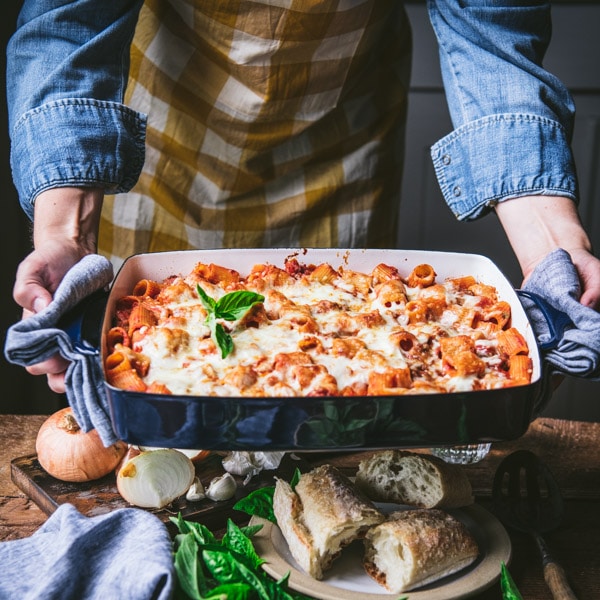 Square image of a pan of Italian rigatoni bake with a side of bread