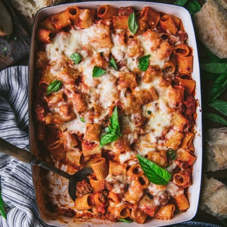 Overhead shot of two hands holding a pan of easy baked rigatoni with sausage