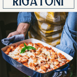 Hands holding a pan of cheesy baked rigatoni with sausage and text title box at top
