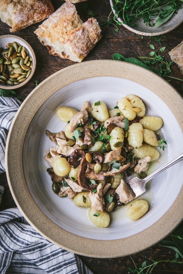 Close overhead shot of potato gnocchi with chicken and mushrooms in a white bowl