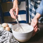 Whisking flour and dry ingredients in a white bowl