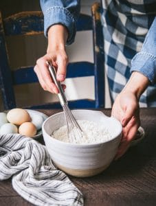 Whisking flour and dry ingredients in a white bowl