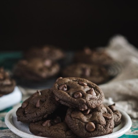 Side shot of a plate of soft and chewy double chocolate chip cookies