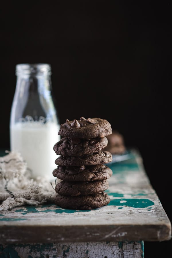 Stack of double chocolate chip cookies with a glass of milk