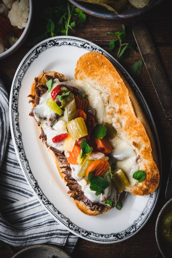 An overhead shot of an Italian beef sandwich topped with homemade giardiniera and Swiss cheese on a toasted hoagie roll.