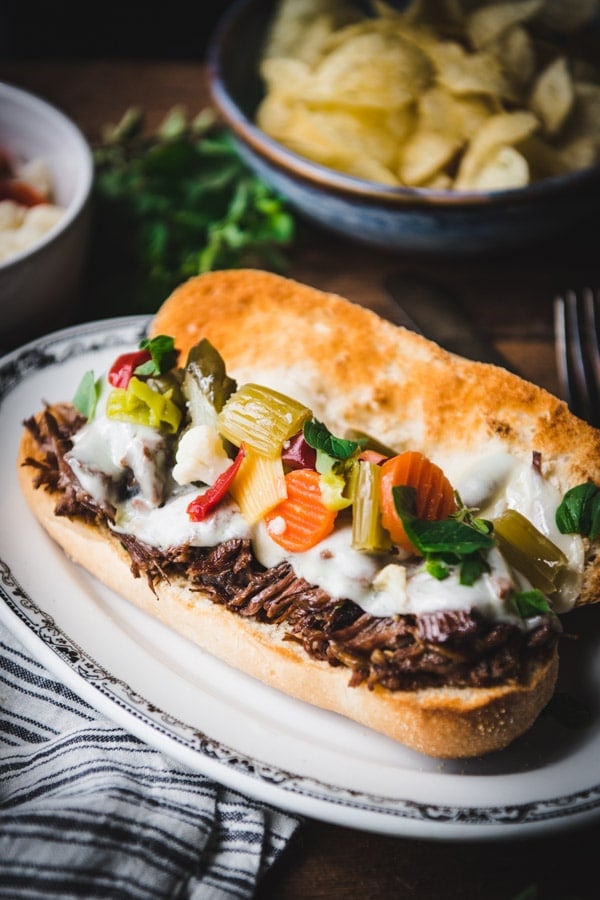 An Italian beef sandwich, topped with melted Swiss cheese and homemade giardiniera on a hoagie roll.