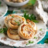 Square image of a plate of Italian appetizers called pinwheels.