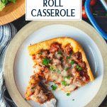 Close overhead shot of sausage crescent roll casserole on a plate with a fork and text title overlay