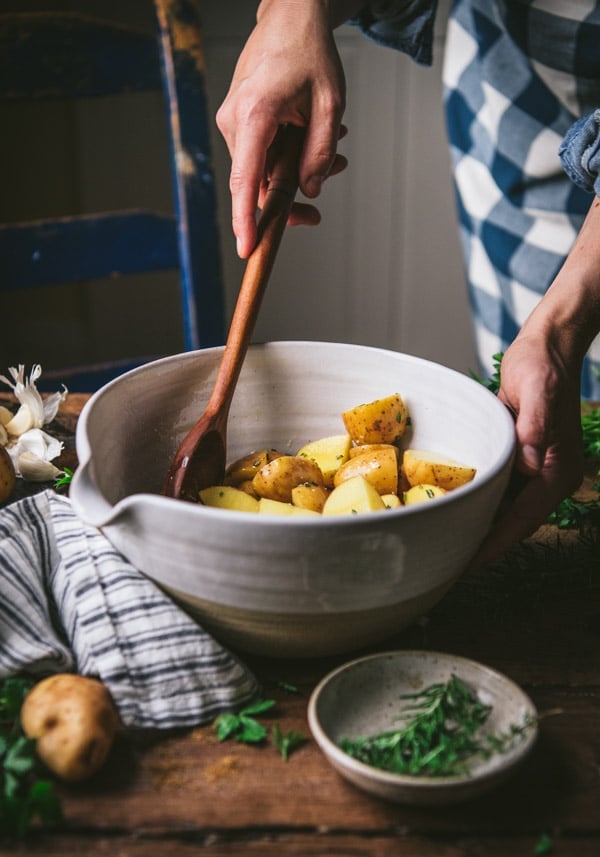 Stirring together a bowl of potatoes with garlic olive oil and rosemary