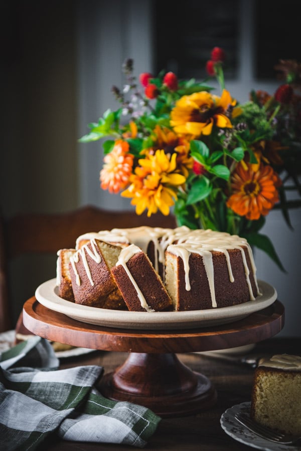 Side shot of a sliced Southern pound cake on a cake stand on a wooden table
