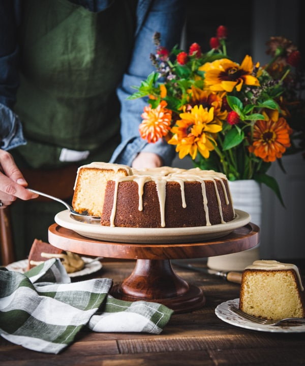 Hands lifting a slice of the best vanilla pound cake recipe on a cake server