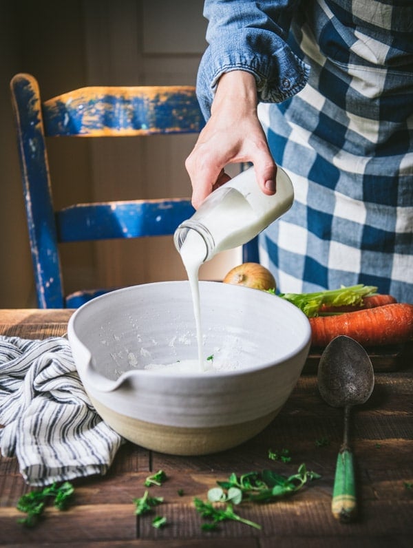 Pouring buttermilk into a white mixing bowl