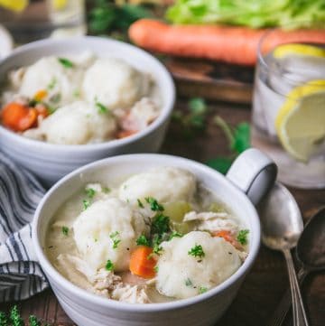 Side shot of bowls of homemade chicken and dumpling soup on a wooden table