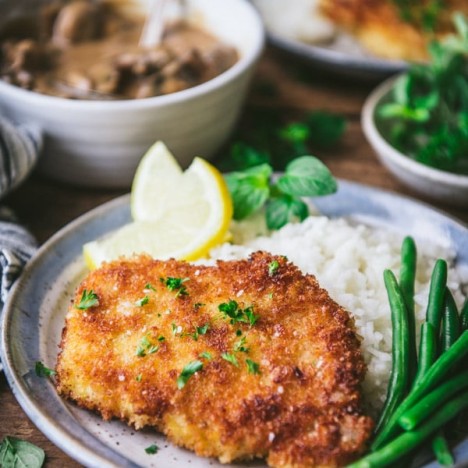 Close up side shot of pork schnitzel with mushroom gravy and a side of rice