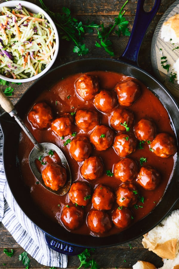 Overhead shot of a skillet full of bbq meatballs on a wooden dinner table