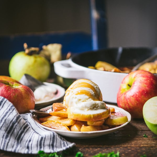 Square shot of a plate of baked apples with vanilla ice cream on a table