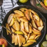 Overhead image of baked cinnamon apple slices in a pan on a wooden table
