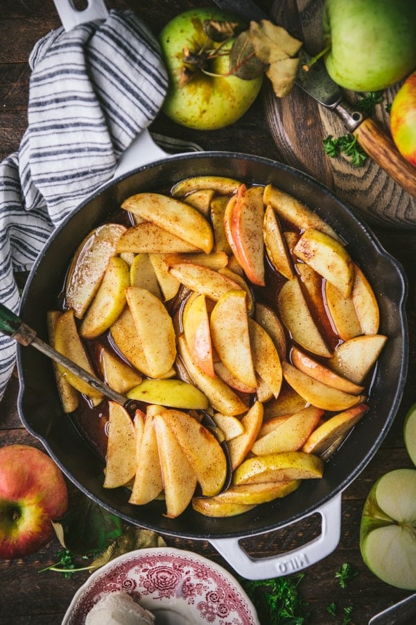 Overhead image of baked cinnamon apple slices in a pan on a wooden table