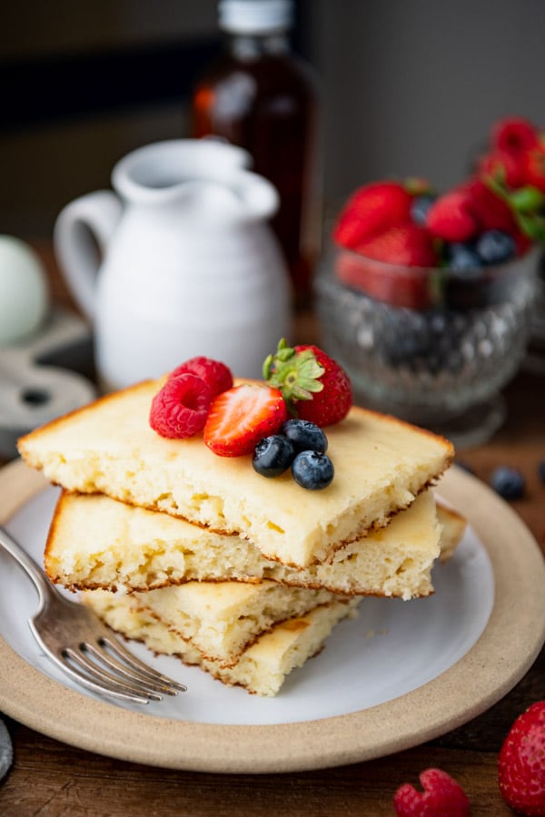 Stack of bisquick baked pancakes on a white plate with fresh berries
