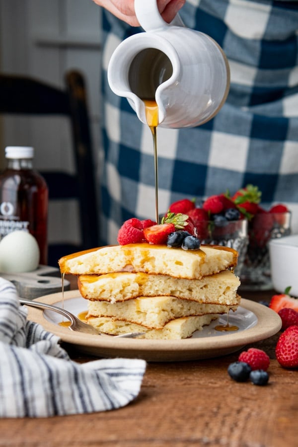 Pouring maple syrup on a stack of oven baked pancakes with pancake mix