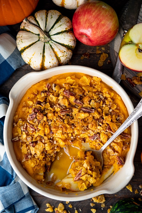Overhead shot of a serving spoon in a dish of layered butternut squash casserole with apples