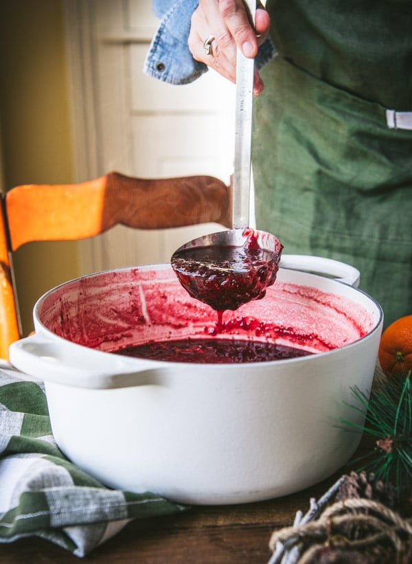 Ladling Christmas jam from a white Dutch oven