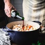Pouring Burgundy red wine into a Dutch oven