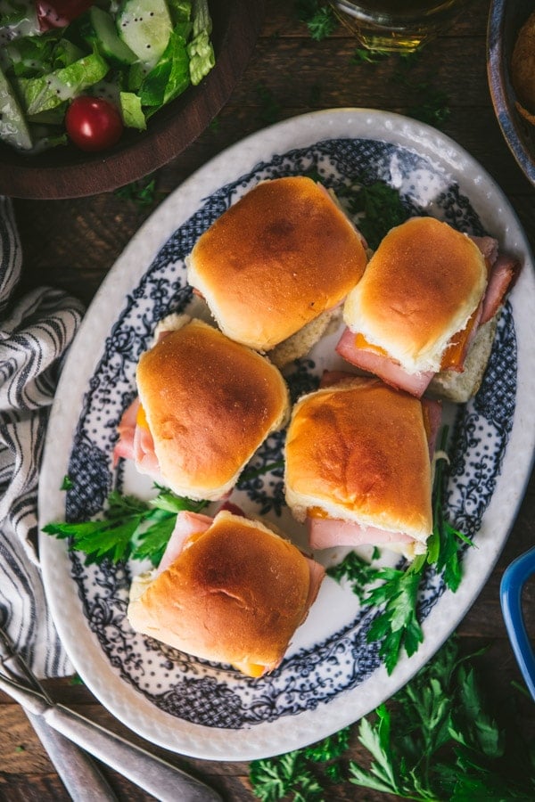 Close overhead image of a blue and white serving tray full of hawaiian ham and cheese sliders