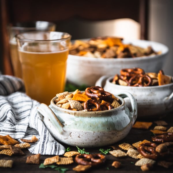 Square image of two bowls of chex mix on a wooden table