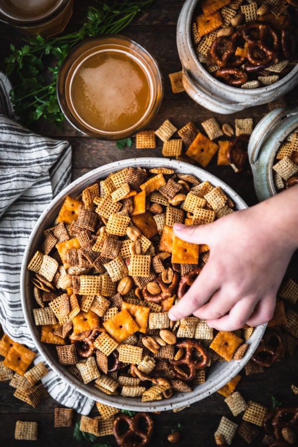 Hands reaching for a bowl of homemade Chex mix