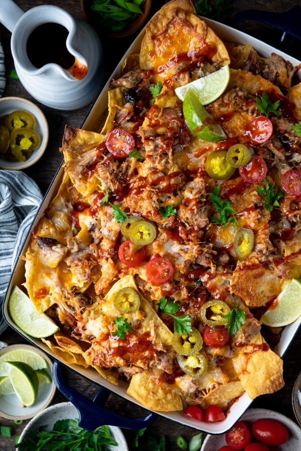 BBQ Pulled Pork Nachos in a pan with jalapenos bbq sauce and other toppings