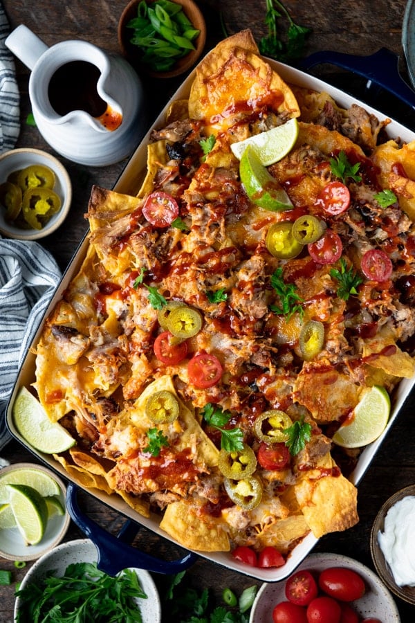 Overhead shot of a pan of pulled pork nachos on a wooden table