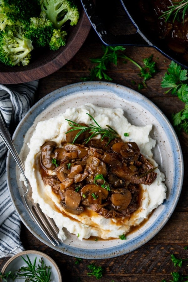 Overhead shot of smothered round steak on a plate with mashed potatoes