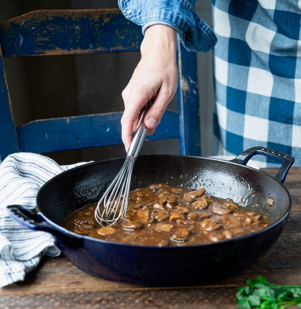 Whisking mushroom and onion gravy in a skillet