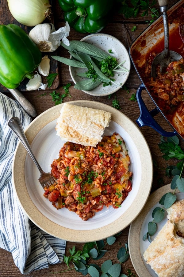 Overhead shot of a bowl of stuffed bell pepper casserole on a table with a side of bread.