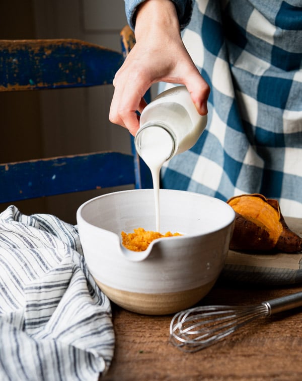 Pouring buttermilk into a white mixing bowl