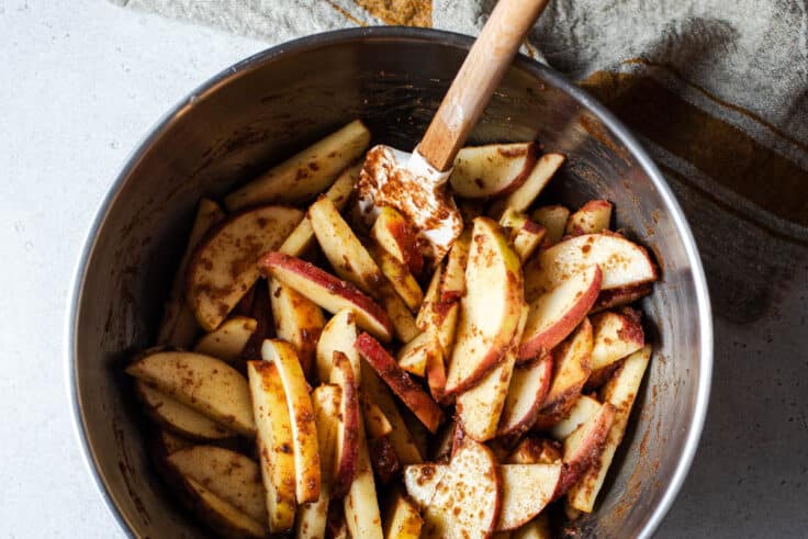 Stirring together the apple slices with the cinnamon and butter mixture.