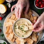 Hands dipping pita in a bowl of the best hummus recipe