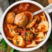 Square overhead shot of a bowl of meatball tortellini soup.