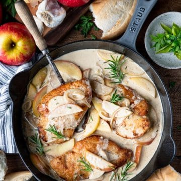 Overhead image of a cast iron skillet chicken dinner with apples and onions