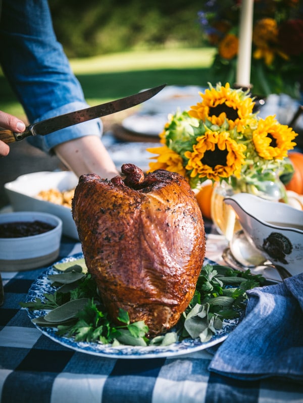 Hands holding a knife to carve a smoked turkey breast