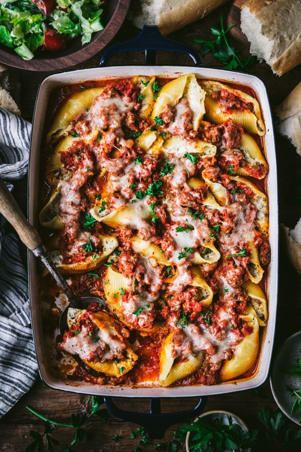 Serving spoon in a pan of stuffed shells with meat