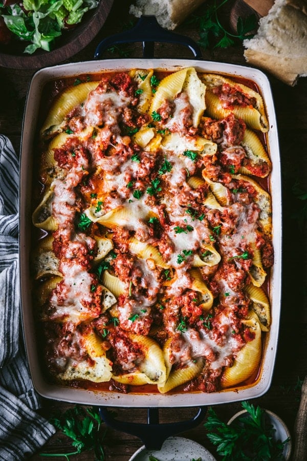 Overhead image of ricotta stuffed shells with ground beef and a parsley garnish