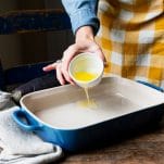 Pouring melted butter in a baking dish.