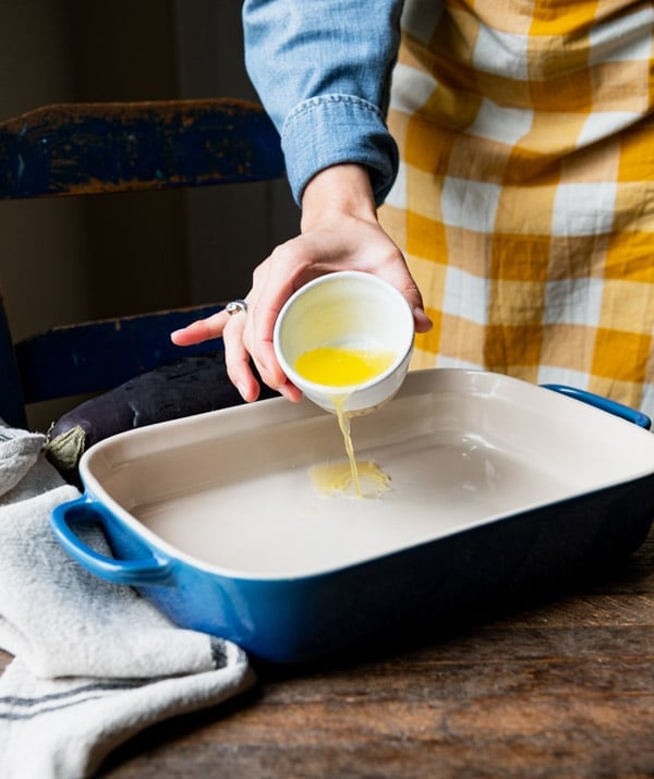 Pouring melted butter in a baking dish.