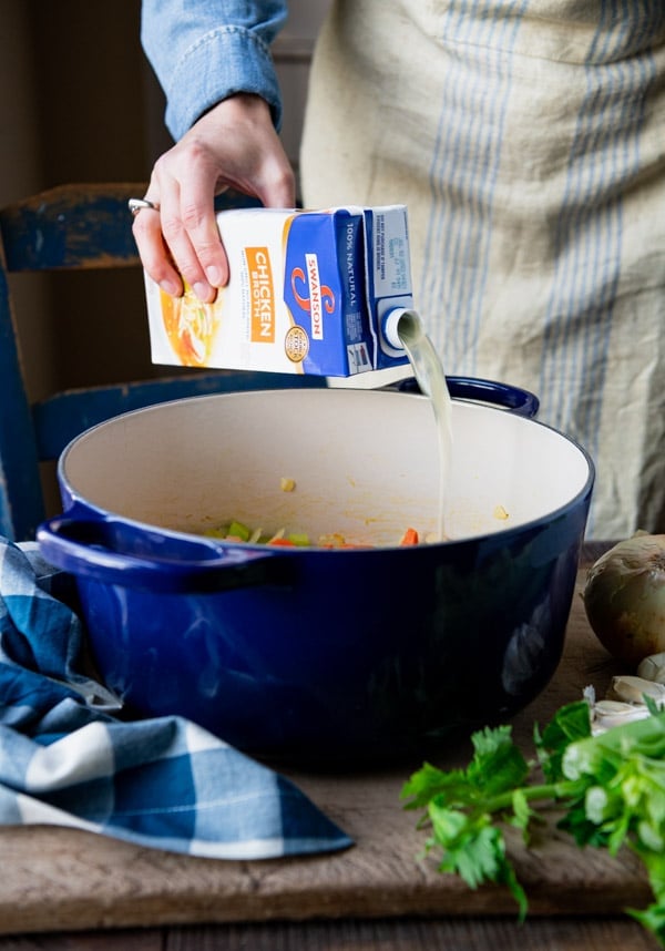 Pouring broth into a Dutch oven