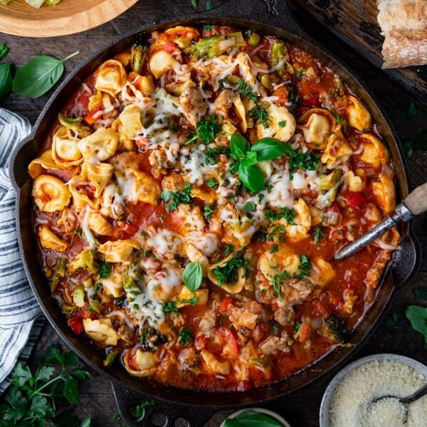 Overhead image of a cast iron skillet with the best cheese tortellini recipe and Italian sausage